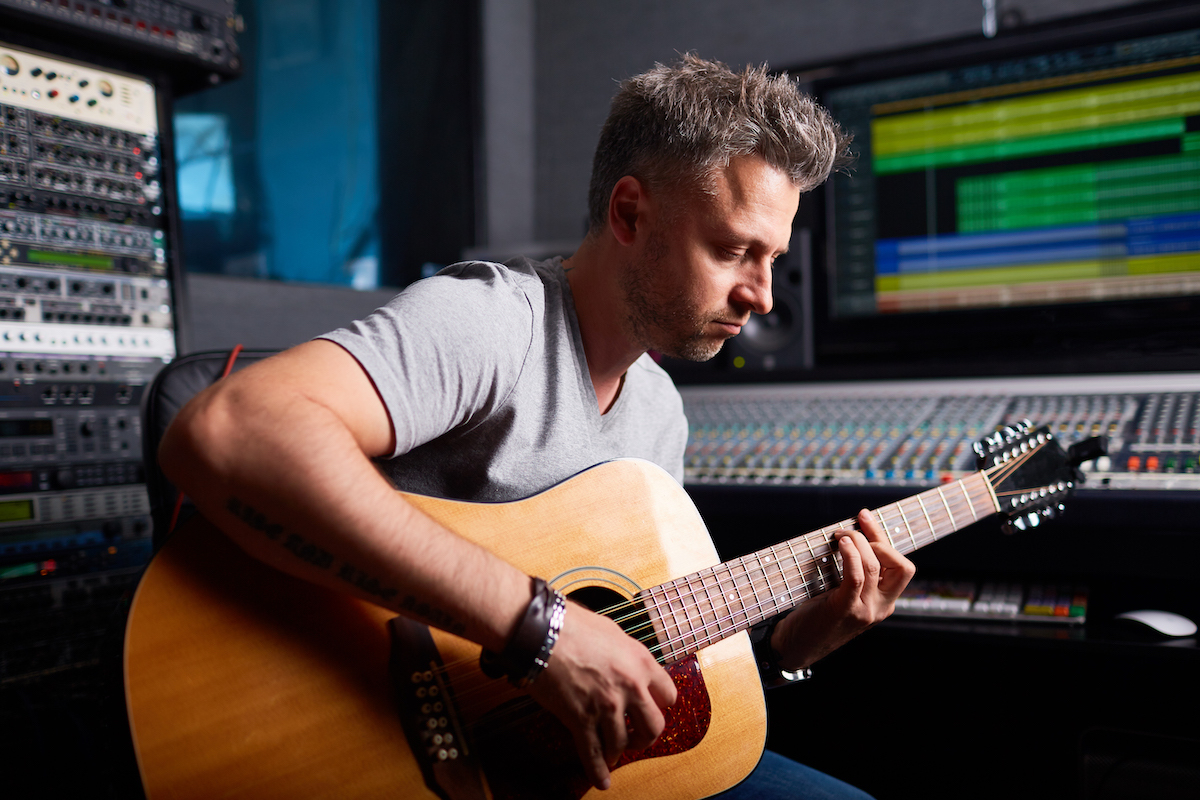 musician recording in studio with acoustic guitar